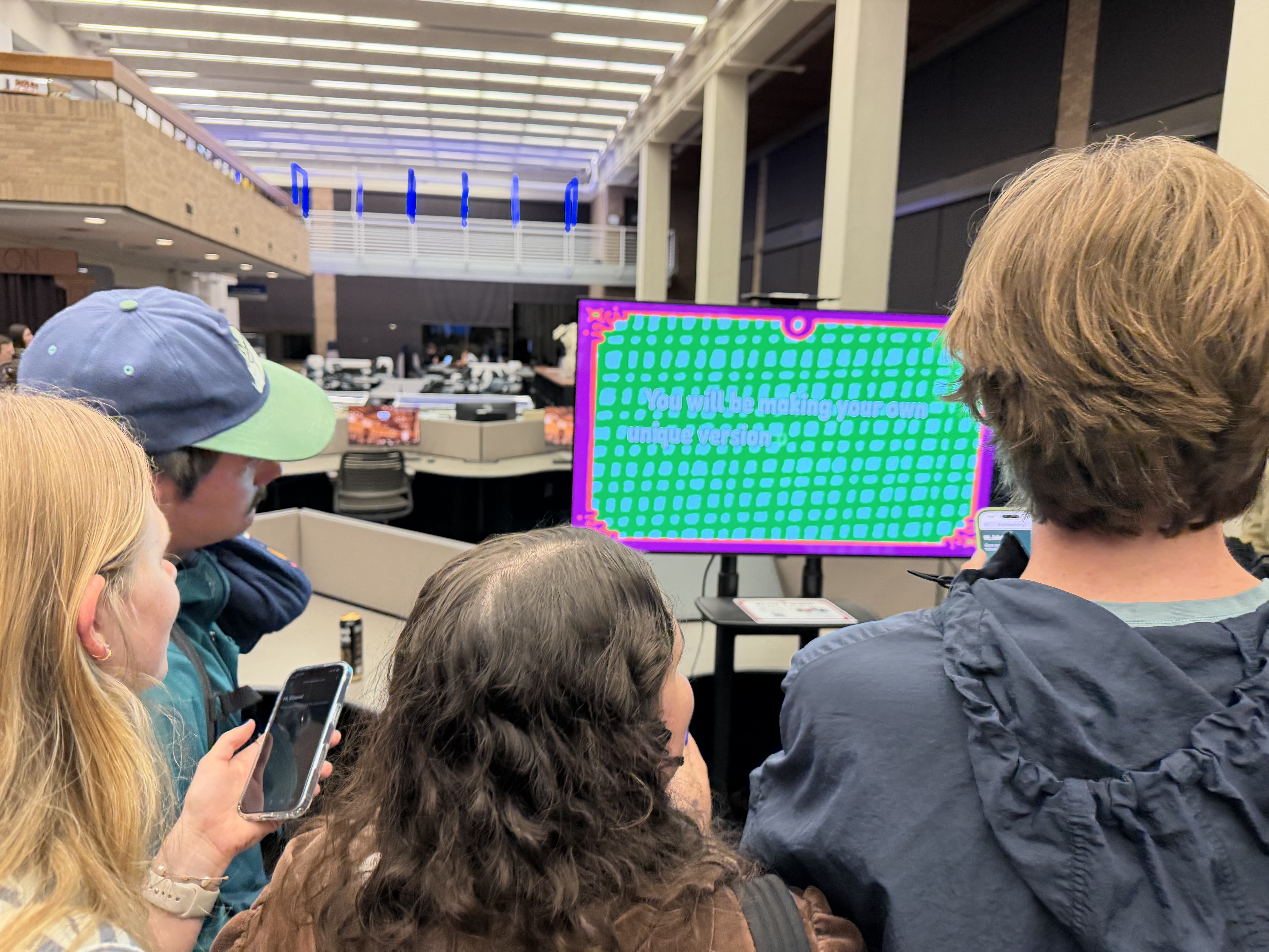 Players gathered around the shared screen, phones in hand, mid-game